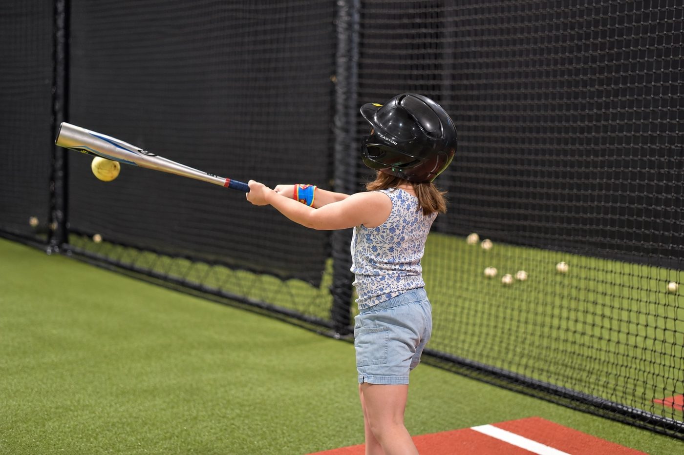A young player mid-swing inside a Hitters batting cage
